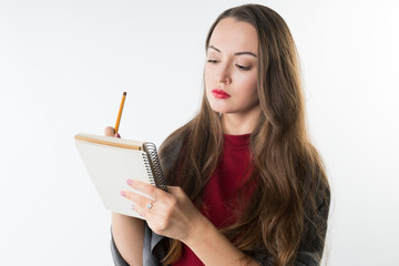 young caucasian pretty girl with sketchbook and pencil on white background. She is thinking and writing