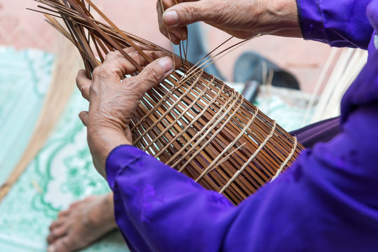Close up Old Vietnamese male craftsman hands making the traditional bamboo fish trap or weave at the old traditional house in Thu Sy trade village, Hung Yen, Vietnam