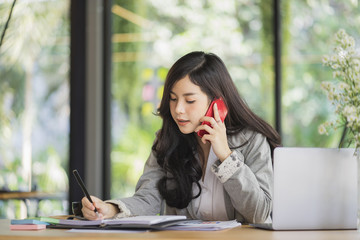 Portrait of an attractive young woman holding her phone while working in coffee shop.