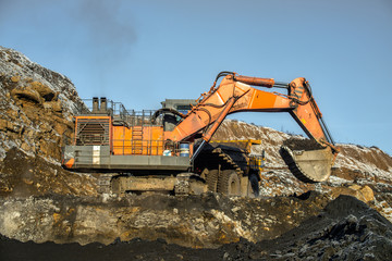Big yellow dump trucks and excavator in coal mine
