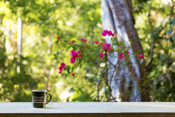 Coffee mug on a ledge overlooking a tropical rainforest