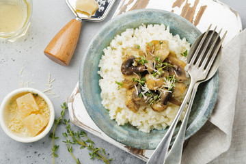 Risotto with chicken and mushrooms, thyme, garlic, parmesan cheese on old gray concrete background. Traditional Italian dish. Selective focus. Rustic style. Top view.