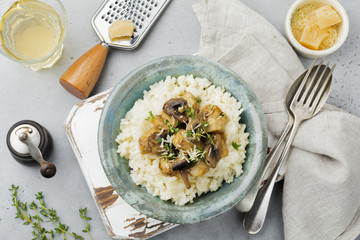 Risotto with chicken and mushrooms, thyme, garlic, parmesan cheese on old gray concrete background. Traditional Italian dish. Selective focus. Rustic style. Top view.