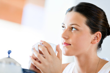 Happy young woman with cup of tea or coffee at home