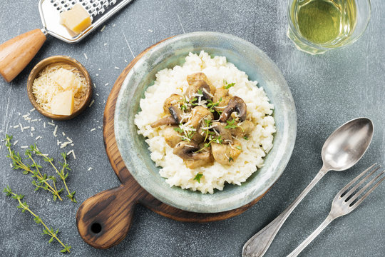 Risotto with chicken and mushrooms, thyme, garlic, parmesan cheese on old gray concrete background. Traditional Italian dish. Selective focus. Rustic style. Top view.