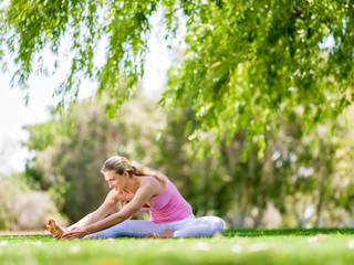 Obraz premium Young woman doing yoga in the park