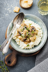 Risotto with chicken and mushrooms, thyme, garlic, parmesan cheese on old gray concrete background. Traditional Italian dish. Selective focus. Rustic style. Top view.