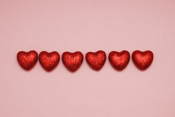 Arrangement of Red Glittere Shinny Decorative Hearts on Pink Background. Valentine Day Concept. Love and Hearts.