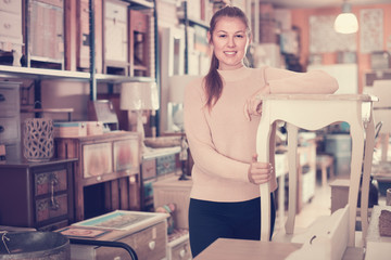 Positive woman customer touching dressing table in furniture shopping room
