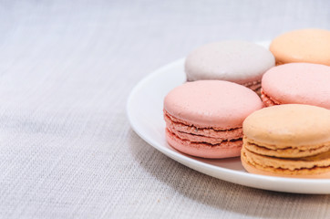 Delicious cake macaroons on plate on light background, close up