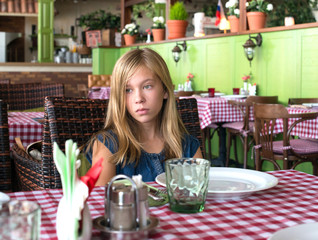 Sad teenager girl in a restaurant. Lonely girl waiting in a café.