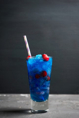 Blue cocktail with cranberry on the wooden background. Selective focus.