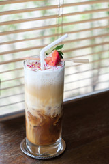 Iced coffee latte with strawberry on wood table