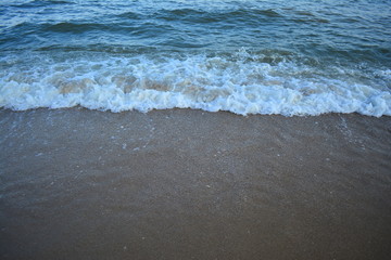 Fototapeta na wymiar Hard wave of blue ocean on sandy beach background in last sun light