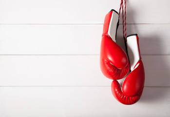Red professional boxing gloves hanging on white wooden wall. Background with copy space.