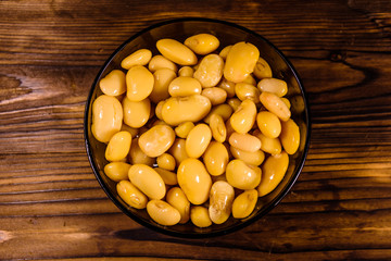 White marinated haricot beans in glass bowl on a wooden table. Top view