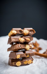 Pile of dark chocolate with nuts on the wooden table. Selective focus. Shallow depth of field.