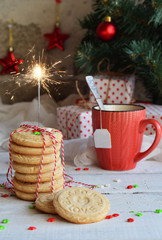 Christmas and new year holiday celebration concept background. Mug of tea, homemade nut cookie, shortbread, xmas tree decoration on wooden table