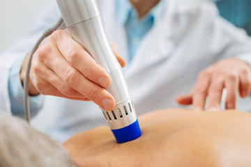 Medical therapy. Close up of a special device being used by a nice pleasant doctor while working with his patient