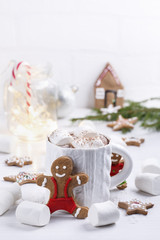 Cup of traditional hot chocolate with marshmallows and gingerbread on white table.  Christmas drink in New Year decorations.