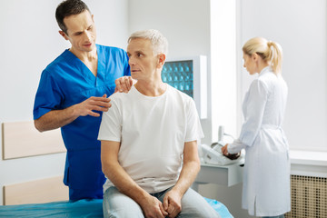 Describe your feelings. Smart handsome nice man standing behind his patient and touching his...