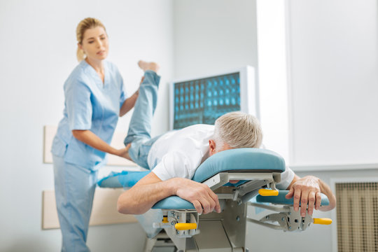 Medical examination. Nice pleasant elderly m an lying on a special be and undergoing medical examination while visiting a hospital