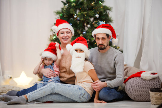 Picture of happy family in Santa caps at Christmas tree