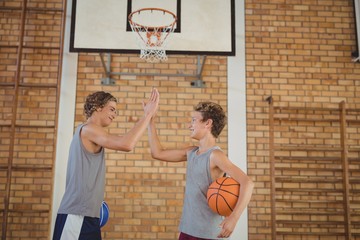High school boys with basketball giving a high five