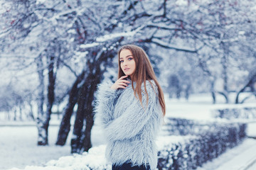 fashion woman in fur coat posing in winter park