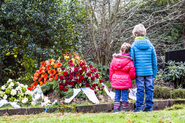 Little brother and sister standing at the grave of their parents
