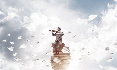 Obraz na płótnie Canvas Handsome violinist play his melody and paper planes fly around