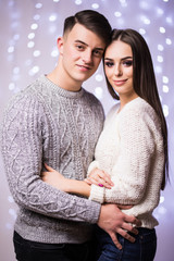 Happy smiling young man woman, couple, dark night, lights bokeh, winter clothes hugging standing outdoors