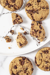 Cookies with dark chocolate chips and stings on white plate.