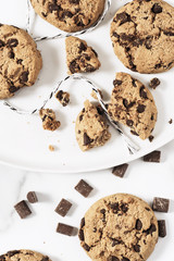 Cookies with dark chocolate chips and string on white plate.