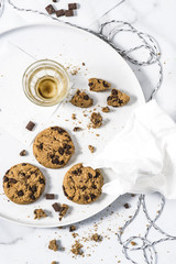Cookies with dark chocolate chips and crumbs on white plate.