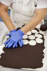 Young woman cutting out cookie dough circles at a bakery