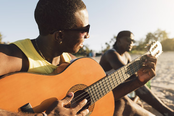 Two cuban friends having fun in the beach with his guitar.