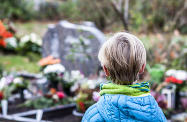 Little boy standing at the grave of his parents