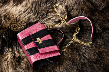 Pink leather bag on a bear's fur. Fashion concept