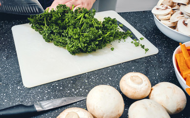 Prezzemolo tagliato su tagliere e altri ortaggi