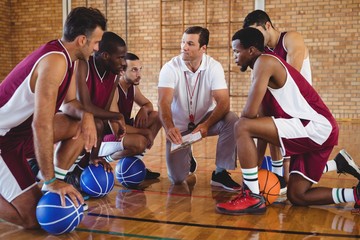 Fototapeta premium Coach explaining game plan to basketball players