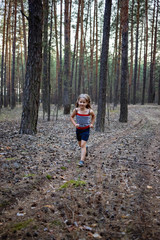 Little girl run in the pine forest.