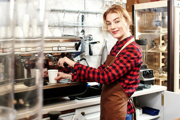 Portrait of a girl baristas at workplace on background of coffee