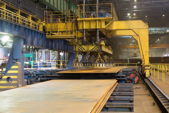 Overhead crane with magnetic lift in the shop for manufacturing large diameter pipes - Powered by Adobe