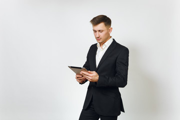 Young successful handsome rich business man in black suit working on modern tablet isolated on white background for advertising. Concept of money, achievement, career and wealth in 25-30 years.
