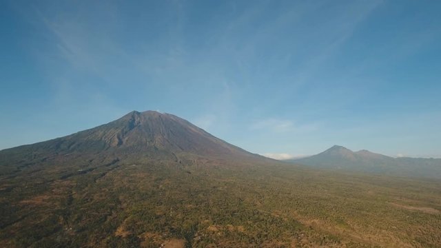 Aerial view of Volcano Mount Agung with smoke billowing out at sunrise, Bali, Indonesia. Conical volcano of Gunung Agung. Rural mountain landscape. 4K, Aerial footage.