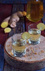 Homemade ginger tincture or ale on wooden background. Rustic style. Spice yellow liqueur in a glass. Alcohol drink.