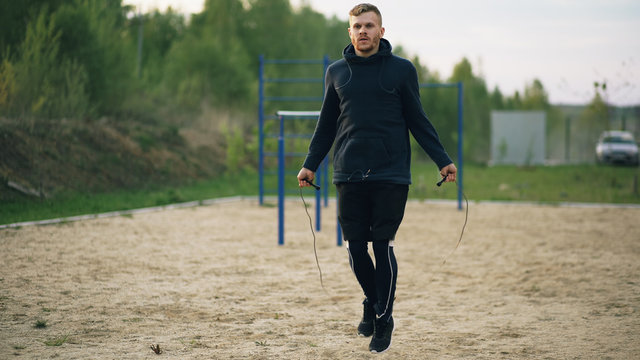 young man kick boxer training with skipping rope in city park