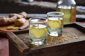 Homemade ginger tincture or ale on wooden background. Rustic style. Spice yellow liqueur in a glass. Alcohol drink.