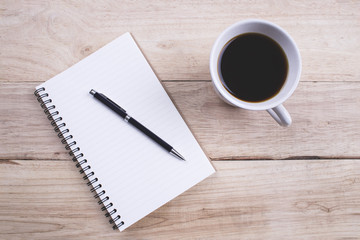 Top view Note book with pen and a cup of coffee on wood table for Business